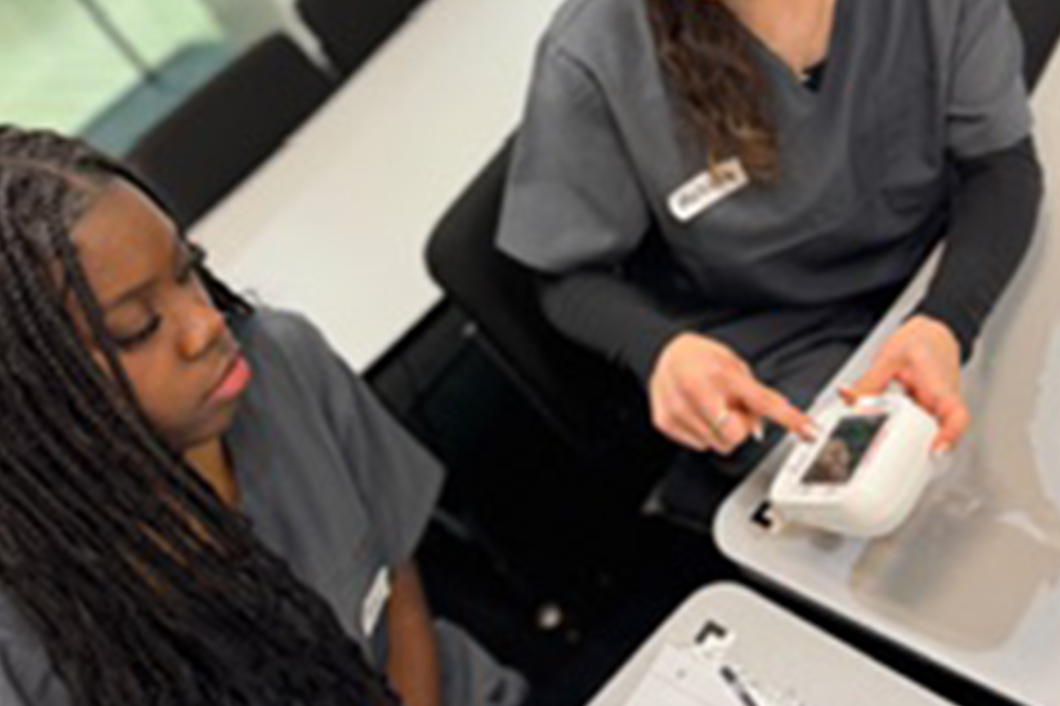 CNA student learning to use medical monitoring equipment during training